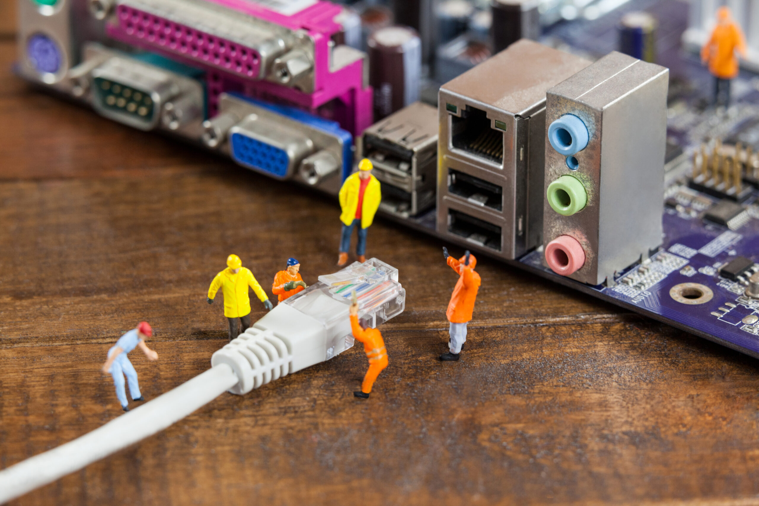 Conceptual image of miniature engineer and worker plug-in lan cable to computer